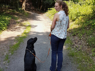 Frau mit Hund auf Waldweg